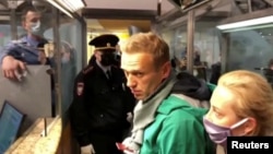 Russian police speak with Aleksei Navalny (with his wife, Yulia, right) before leading him away at Sheremetyevo airport in Moscow on January 17. 