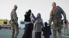 Kazakh military personnel escort a family as they are repatriated from Syria during Operation Zhusan in 2019.