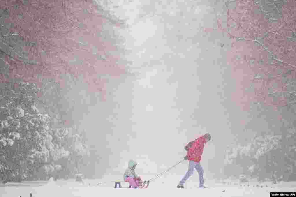 A man pulls a child on a sled during a snowfall in the Romanian capital, Bucharest. 