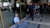 A man sits on the sidewalk crying outside a national bank branch as pensioners queue to withdraw their pensions, with a limit of 120 euros, in Thessaloniki.