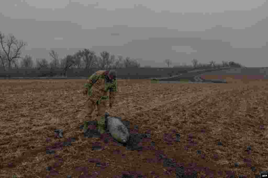 A Ukrainian military deminer checks an unexploded Russian aerial guided bomb in a field in the Dnipropetrovsk region.&nbsp;