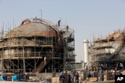 Workers fix the damage at a Saudi Aramco processing facility after an attack in Abqaiq by Huthi rebels in September 2019.