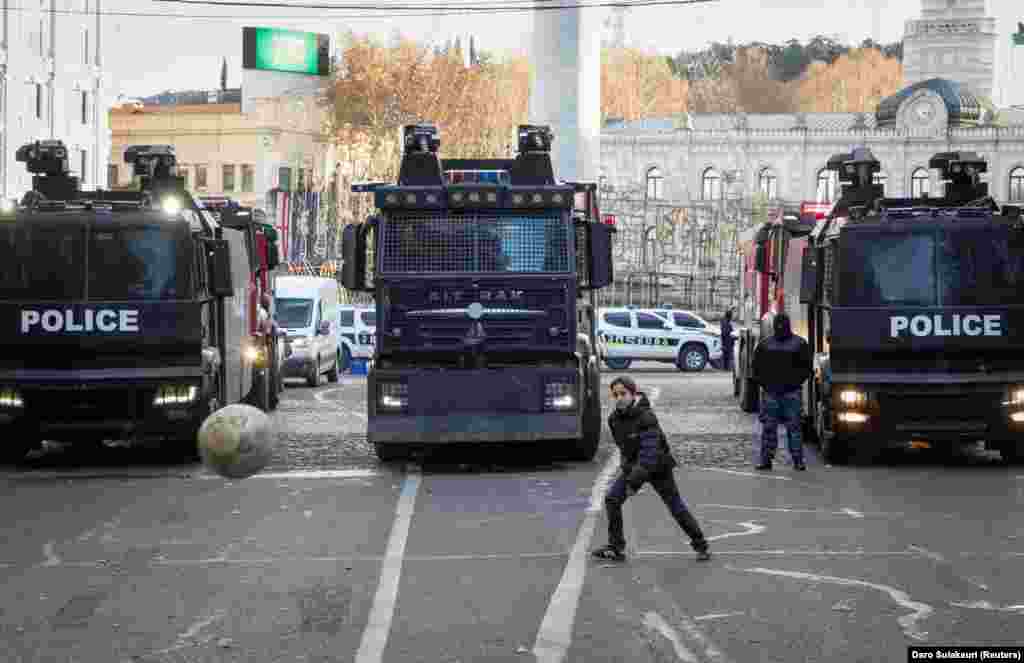 A boy plays in front of riot police trucks outside the parliament building in the restive Georgian capital, Tbilisi.&nbsp;