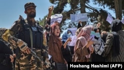 A Taliban fighter stands guard as Afghan women shout slogans during a protest rally near the Pakistani Embassy in Kabul on September 7.