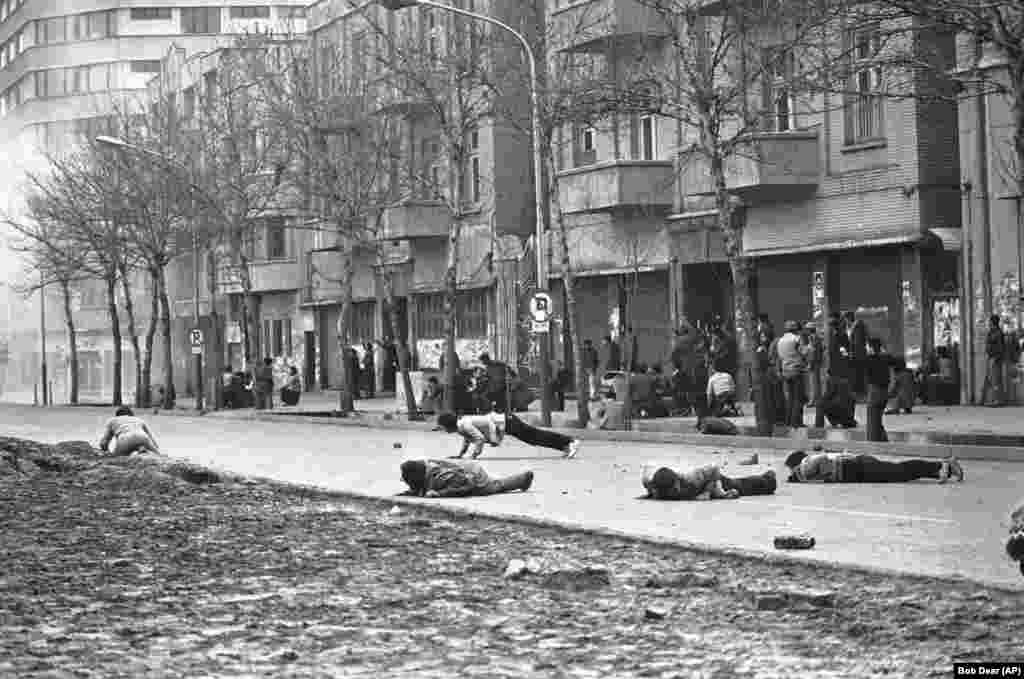 Severe clashes erupt on January 26, 1979 amid Iran&#39;s political instability and leadership vacuum. Antigovernment demonstrators dive for cover as Iranian army soldiers fire live rounds in Tehran.