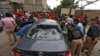 Police officers survey a damaged car at the site of an attack at the Pakistan Stock Exchange entrance in Karachi after a militant attack on June 29.