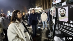 A woman in Tbilisi on December 9 looks at a poster showing people reportedly beaten by Georgian police.