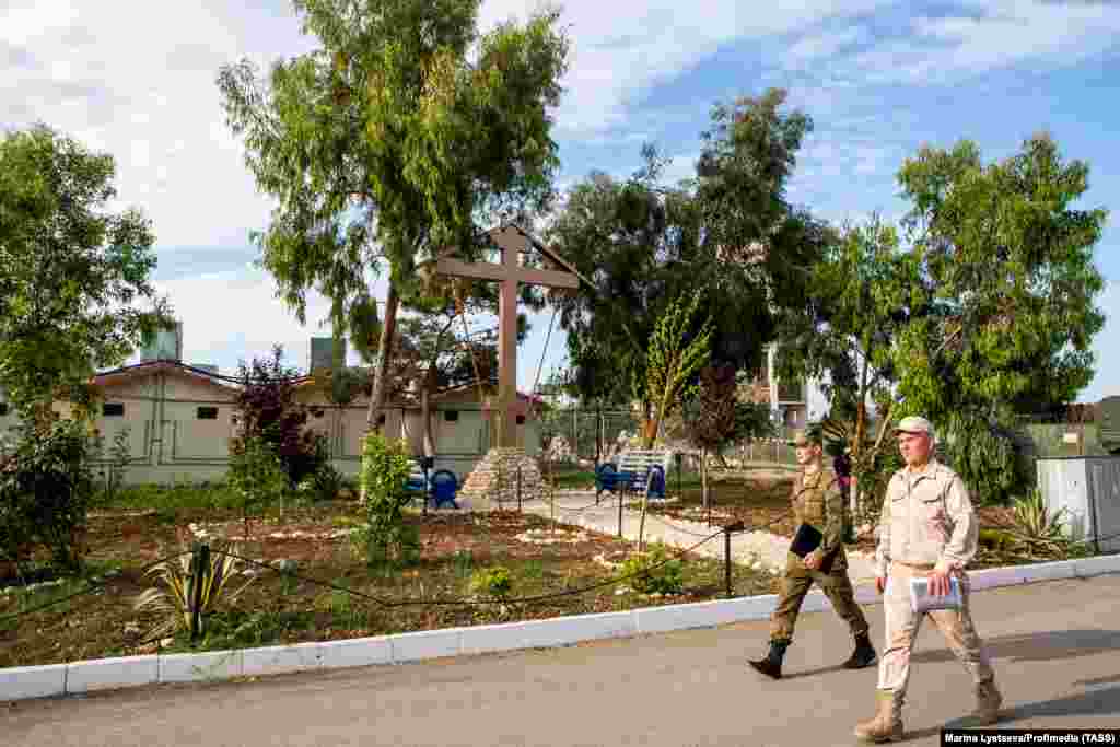 Russian soldiers walk past an Orthodox cross at the Hmeimim base in April 2018. The Hmeimim air base has been a hub for Russian military aircraft since 2015, when the Kremlin moved to shore up Assad&rsquo;s forces in the Syrian civil war.&nbsp; &nbsp;