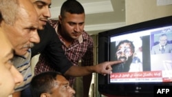 Iraqis watch Arabic satellite news channel Al-Arabiyah as it shows an image that was circulating on the Internet purporting to show the dead body of Al-Qaeda mastermind Osama bin Laden.