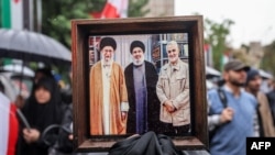 A demonstrator in Tehran holds a picture depicting Iranian Supreme Leader Ali Khamenei (left), Hezbollah leader Hassan Nasrallah (center), and Iranian General Qasem Soleimani, who was slain in a U.S. drone strike in Iraq in January 2020.