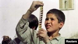 An Afghan boy examines a strip of film snatched from the flames of a bonfire lit by the Taliban to destroy cinema reels in Kabul in 1996. 