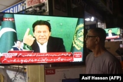 A man listens to Pakistani Prime Minister Imran Khan addressing the nation on television in Karachi.