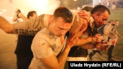 Demonstrators carry a man injured by police during protests after polls closed in Minsk on August 9.