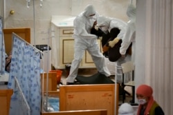 Medical workers carry a patient who is suspected of having the coronavirus inside a restaurant that has been converted into a clinic in Bishkek on July 22.