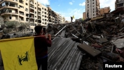 People carry Hezbollah flags at the site of an air strike in Beirut's southern suburbs on November 27.