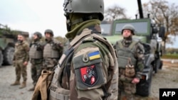 Ukrainian soldiers of the 155th Separate Mechanized Brigade stand next to military vehicles during a training exercise in France. 