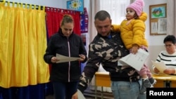 A man holds a child as he casts his vote in the parliamentary elections in Joita, outside Bucharest, on December 1.