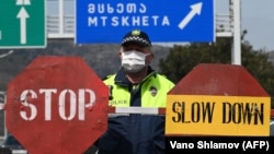 A Georgian policeman stands guard at a checkpoint in Tbilisi on April 1. They say numbers never lie. But as governments tabulate figures for COVID-19 infections and deaths, experts say the data is likely incomplete.