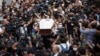 The open coffin of Lekso Lashkarava -- surrounded by mourners and dozens of cameras of fellow TV journalists -- is carried through the streets of Tbilisi on July 13 during his funeral.