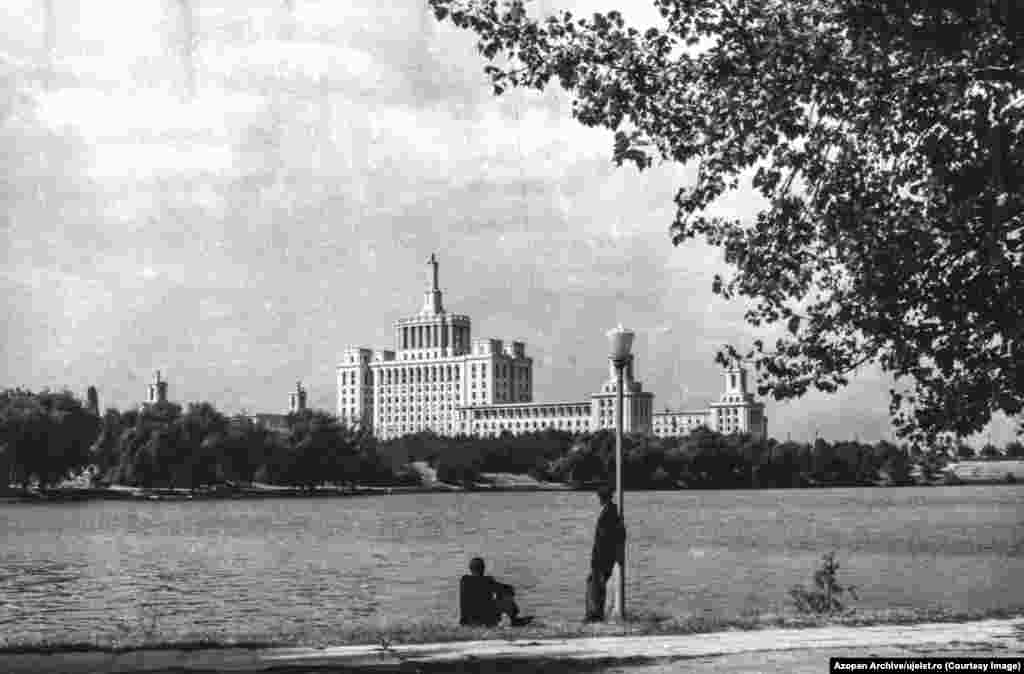 Men look over Herastrau Lake in Bucharest toward the House of the Spark, a building that housed a state-run newspaper in Ceausescu&#39;s Romania. Szocs is one of the founders of Azopan, an open-access photo archive of largely amateur photos from Romania&rsquo;s 20th century, meaning the infrastructure needed for the Uj Elet archive was already largely in place. &nbsp;