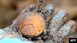 A Bosnian forensic expert shows a pocket watch found at a mass grave site. The UN tribunal has destroyed many such artifacts, citing health risks. 