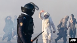 Imran Khan supporters wielding sticks face off with armed police in Islamabad on November 26. 