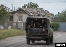 Ukrainian soldiers ride in a military vehicle near the Ukraine-Russia border in the town of Vovchansk, Kharkiv region, on June 5.