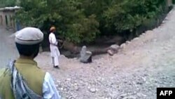 A video grab shows a man pointing an AK47 rifle at a woman identified as 22-year-old Najiba, who is sitting near a ditch shortly before being executed by gunfire in Qol village, Parwan Province.