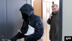 BAZh head Andrey Bastunets (right) and a Belarusian police officer leave the association's Minsk office after a raid on February 16.