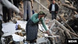 A woman walks among destroyed houses in the Iranian city of Varzaqan in Iran's northwestern province of East Azerbaijan on August 12.