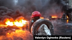 A day after intense clashes between protesters and riot police left at least three people dead, activists in Kyiv on January 23 set fire to tires and barricades, filling the streets with smoke.