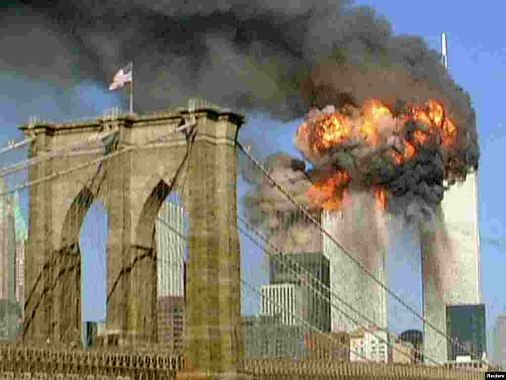 The World Trade Center towers burn behind the Brooklyn Bridge on September 11, 2001.