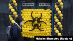 A pedestrian wearing a protective mask walks past a warning sign made of balloons outside a closed cafe in Moscow on March 30.