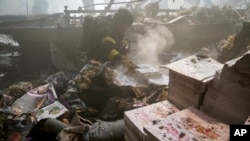 Firefighters work to extinguish a fire as a lifeless body lies under the rubble after a Russian missile hit a large printing house in Kharkiv, Ukraine, on May 23.