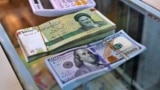 A pile of Iranian rials sits next to a stack of U.S. dollars. Iran's national currency hit a record low on February 11.