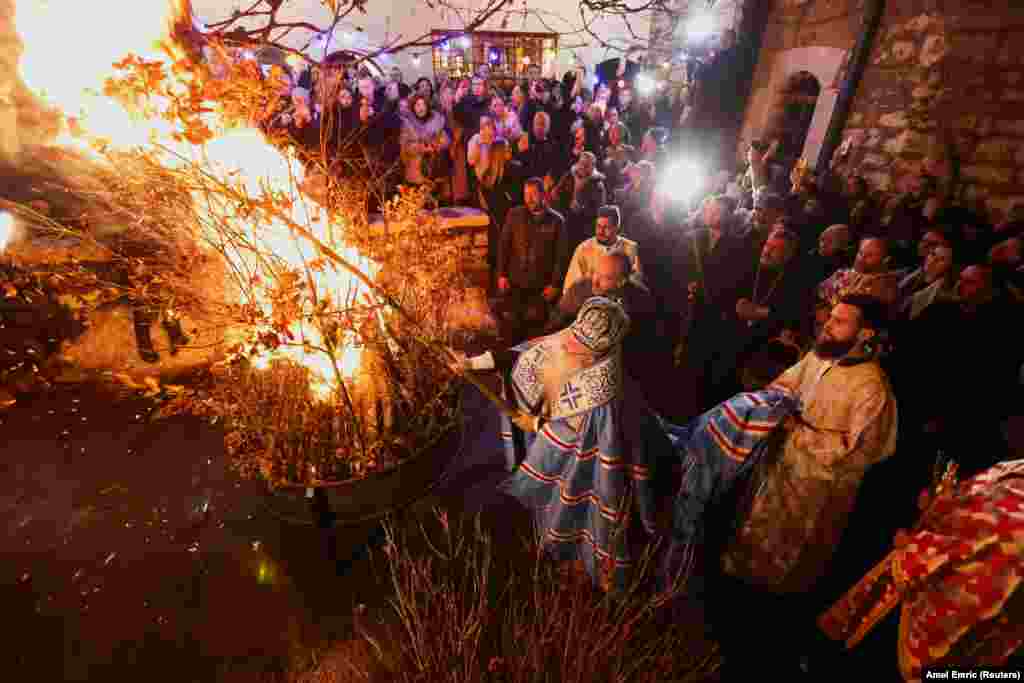 Hrizostom Jevic, a Bosnian prelate of the Serbian Orthodox Church, puts dried oak wood on a fire outside a church in Sarajevo on January 6 as part of the Balkan tradition of burning oak branches, symbolizing the Yuletide log, on Orthodox Christmas Eve.&nbsp;